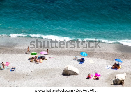 Bokeh effect of Ocean beach view with beautiful waves of clean transparent water and white sand, high altitude view of beautiful seashore with sunbathe people vacation and holiday concept, blur effect