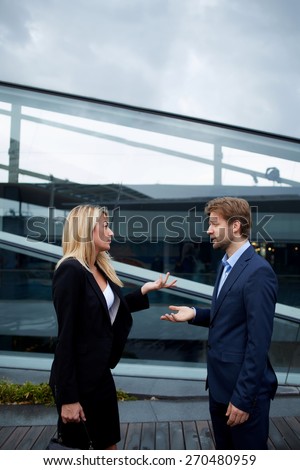 Side view portrait business people discussing work during break, caucasian businesswoman serious speaking to a colleague while they standing outside office, angry boss talk to her employee gesturing