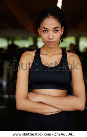 Portrait of young ethic woman standing with crossed arms relaxing after fitness workout at gym