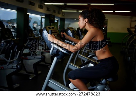 Attractive young woman with beautiful figure using an exercise bike at the gym