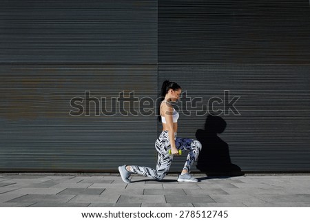 Healthy woman doing strength training with dumbbells against black line background outdoors, athletic female lifting weights while working out against wall with copy space for your text message