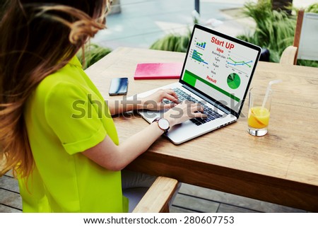 Businesswoman sitting front laptop computer with financial information as graphics and charts on screen, young female entrepreneur work with statistics data and analyzing performance on her notebook