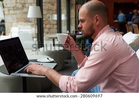 Experienced businessman sitting front laptop computer with blank screen copy space for your content,young entrepreneur work on notebook holding cup of cafe while he sitting in modern coffee shop