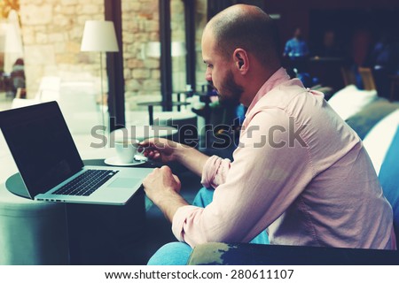 Modern business man connecting to wireless on his laptop computer during coffee break in modern interior, male freelancer working on notebook sitting in cafe, entrepreneur hold cup of tea or coffee