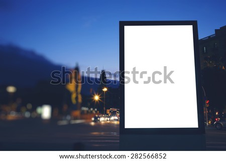 Illuminated blank billboard with copy space for your text message or content, public information board in night city with beautiful dusk on background, advertising mock up banner in metropolitan city
