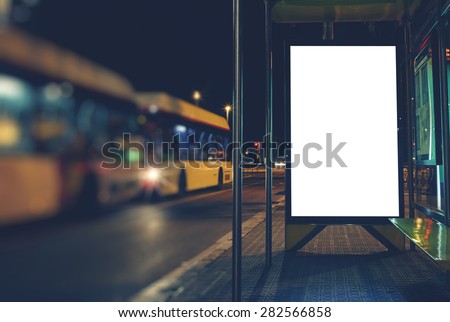 Illuminated blank billboard with copy space for your text message or content, advertising mock up banner of bus station, public information board in night city, auto bus stop empty poster