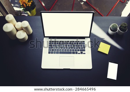 Top view of workplace with open laptop, empty smart phone and stickers,computer with blank copy space screen for your information or content,modern table at open window in home interior, distance work