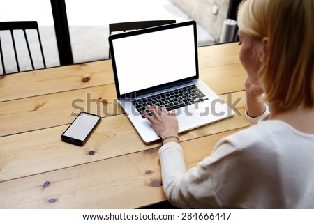Female person sitting front open laptop computer and smart phone with blank empty screen for your information or content, modern businesswoman work in internet via notebook, student at coffee shop