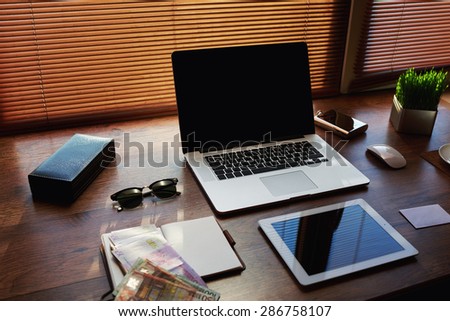 Mock up of workspace with laptop computer and digital tablet, electronic business and distance work concept, successful businessman or entrepreneur wooden table with style accessories and euro bills
