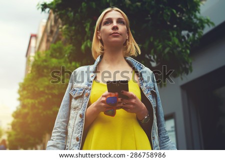 Lost female tourist use smart phone for navigation to check out the sights, gorgeous young woman holding mobile phone standing in the city with beautiful trees, hipster girl chatting for meet a friend