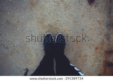 First person view from above of male legs in running shoes standing on wet asphalt in rainy and foggy day,man\'s legs in sports sneakers standing on the road with copy space for your conceptual message