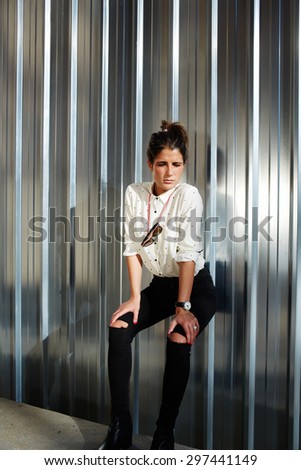 Young modern women with perfect figure in fashionable branded clothing standing on shiny chrome background with copy space for your text message while posing for the camera outdoors in urban setting