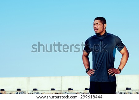 Attractive jogger man with muscular body resting after run while standing against blue sky background with copy space area for your text message or information, sportsman took a break after workouts