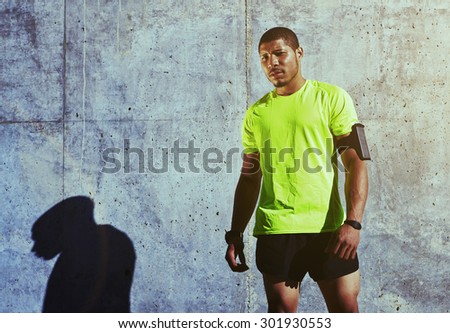 Half length portrait of sweaty man athlete resting after physical exercise while standing against cement wall background with copy space area for your text message or advertising, runner having a rest