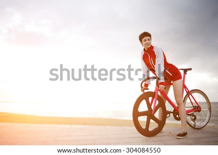 Attractive female dressed in flamboyant active wear rest after ride on her sport fixed gear bicycle, female enjoying weekend stroll on rental bike while standing against dramatic sky with copy space