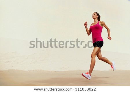Full length portrait of female runner on morning jog against with copy space area wall for your text message or information, healthy sports woman with sexy figure playing sports outdoors in summer day