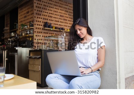 Creative young woman work on laptop computer during breakfast in modern coffee shop outdoors, experienced female freelancer connecting to wireless via net-book during lunch break in sidewalk cafe