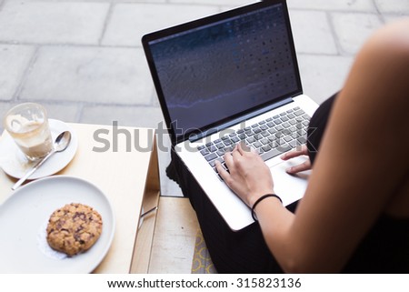 Cropped image of woman\'s hands keyboarding on net-book while sitting in restaurant outdoors ,female person sitting front open laptop computer with blank empty screen for your information or content
