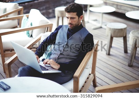 Young successful businessman working on a laptop while sitting in cafe during work break lunch,thoughtful entrepreneur connecting to wireless via computer, intelligent male freelancer work on net-book