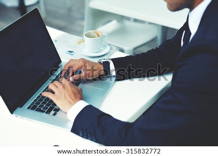 Cropped image view of man\'s hands keyboarding on net-book with blank copy space screen for your advertising content or text message,wealthy man working on a laptop computer during coffee break in cafe