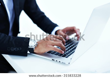 Cropped image view of wealthy successful man working on his laptop at coffee shop, entrepreneur or businessman\'s hand busy using net-book,male person in luxury watches typing text message on computer