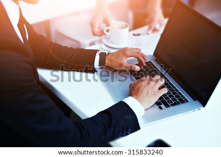 Cropped image view of man\'s hands in elegant suit keyboarding on laptop computer with blank copy space screen for your advertising content or text message, man working on net-book in a cafe, flare sun