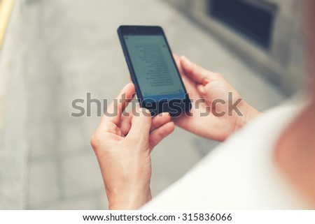 Cropped shot view of woman\'s hands holding smart phone with copy space area for your text message or advertising content, female chatting on her cell telephone while walking in urban setting