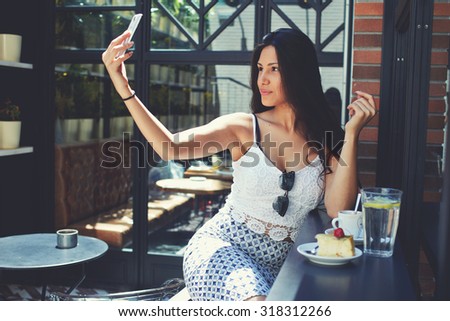 Portrait of attractive sexy lady making self portrait with her smart phone digital camera,young female with big breasts and perfect figure posing while photographing herself for social network picture