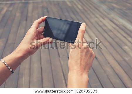Cropped shot view of female tourist taking picture with her smart phone in urban setting, woman\'s hands holding cell telephone with copy space area for your text message or advertising content