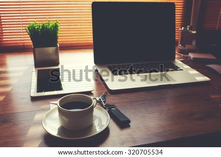 Home freelance desktop with open laptop computer, cup of coffee, digital tablet and green plant lying on the table, electronic business distance work via internet