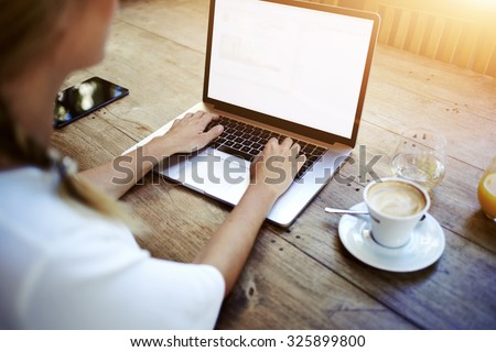 Cropped image of a woman\'s hands keyboarding on net-book while sitting at the wooden table in cafe, female student working on laptop computer with copy space screen background for your text message