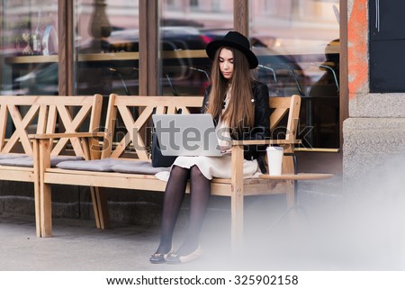 Portrait of a young stylish female student keyboarding on her net-book before the start lectures in University, beautiful woman with trendy look using portable laptop computer for distance work