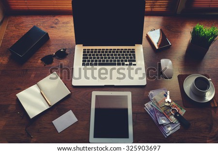 Mock up of freelancer desktop with luxury accessories and work tools, cup of coffee, sunglasses, open notepad, money bills, envelope, digital tablet and laptop computer, hipster office workplace