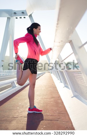 Portrait of young sporty woman dresses in tracksuit stretching muscles of legs before start her daily jog, athletic female doing warm up exercise, sporty girl doing physical training in the fresh air