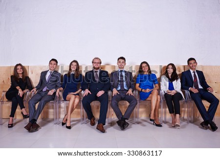 Portrait of a young successful International business people dressed in elegant office clothes waiting for start conference, confident workers in formal wear relaxing after meeting with partners