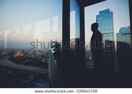Silhouette of a man financier think about something while standing near office window background with copy space for your text message or advertising content, young male thoughtful rest after briefing