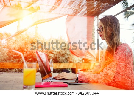 Portrait of a young successful female freelancer using net-book for distance work during morning breakfast, attractive woman keyboarding on laptop computer while sitting in sidewalk cafe in summer day