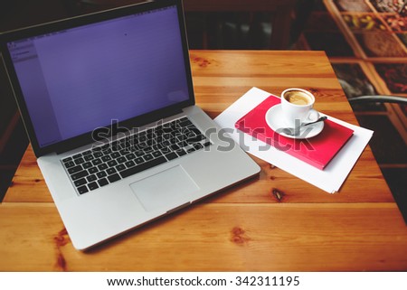 Open laptop computer with blank copy space screen for your information content or text message, portable net-book with cup of cappuccino lying on wooden table in contemporary coffee shop interior
