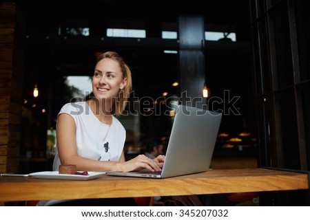 Gorgeous cheerful woman freelancer with good mood using laptop computer for distance work during lunch in cafe bar, attractive female with beautiful smile sitting with portable net-book in coffee shop