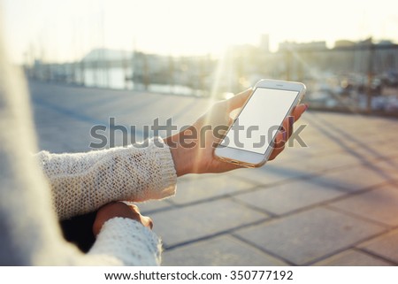 Cropped image of woman\'s hands holding cell telephone with blank copy space screen for your text message or promotional content, hipster girl using mobile phone while resting outdoors during free time
