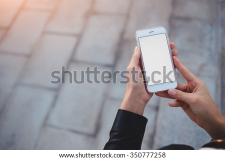Cropped shot view of woman\'s hands holding smart phone with blank copy space screen for your text message or information content, female reading text message on cell telephone during in urban setting