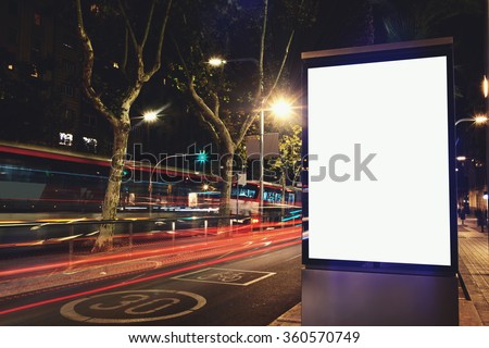 Illuminated blank billboard with copy space for your text message or content, public information board in night city with movement of car on background, advertising mock up banner in urban setting