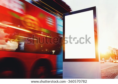 Illuminated blank billboard with copy space for your text message or content, public information board outdoors with motion blur bus on background, advertising mock up banner in metropolitan city