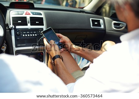 Cropped shot view of man checking location map on cell telephone while sitting near the driver, male passenger using mobile smart phone for navigation application with planned route on the screen