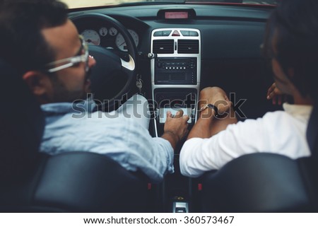 Back view of a handsome man convertible driver listening to the story of his friend while their travel together, two men sitting in luxury car cabriolet while having road trip during summer adventures