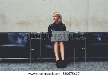 Young female freelancer in good mood dreaming about something while holding on knees open net-book, woman thinking about new ideas for creating design project while sitting with laptop computer
