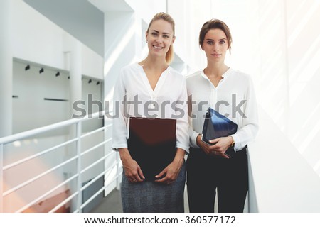 Women employees resting in office interior after entering information from paper documents in touch pad, two female partners holding digital tablet and folder after preparing for meeting with clients