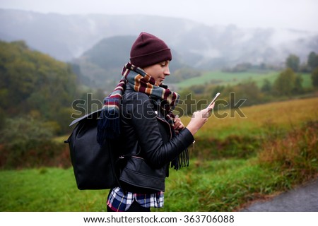 Young female wanderer search position navigation on mobile phone to find right way during adventure tour in mountains, woman hiker checks weather forecast via cell telephone while climbs the mountain