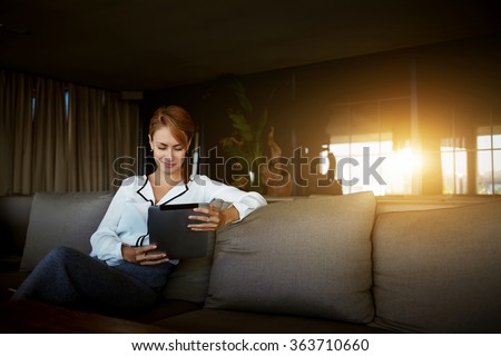 Charming businesswoman reading feminine article in social network via touch pad while waiting for menu in modern coffee shop,female using digital tablet for search information for forthcoming meeting