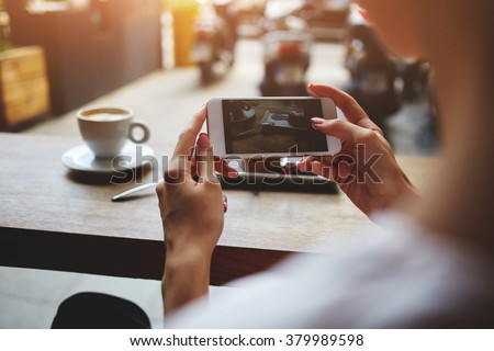 Close up of women\'s hands photographing sweet dessert on mobile phone for social network picture, hipster girl making photo with cell telephone camera of her morning breakfast while sitting in cafe